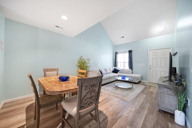 dining room with visible vents, wood finished floors, baseboards, and high vaulted ceiling