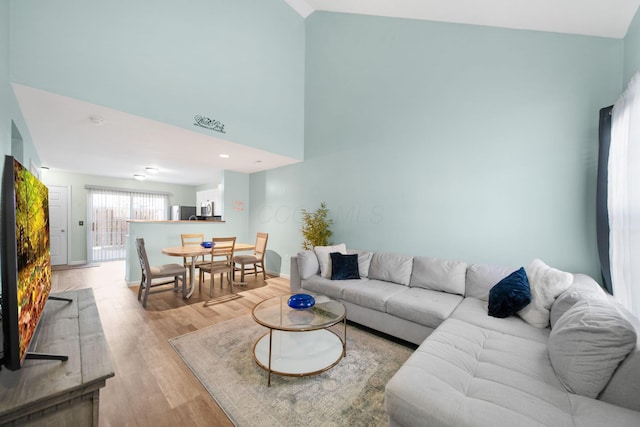 living room with light wood-style flooring and high vaulted ceiling