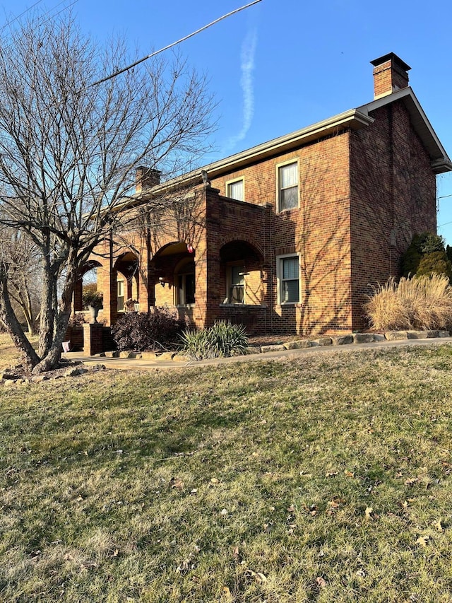 view of front of house with a front lawn, brick siding, and a chimney