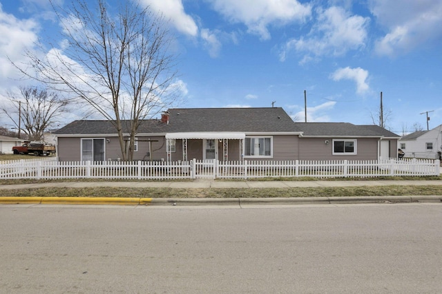 ranch-style home featuring a fenced front yard and a shingled roof