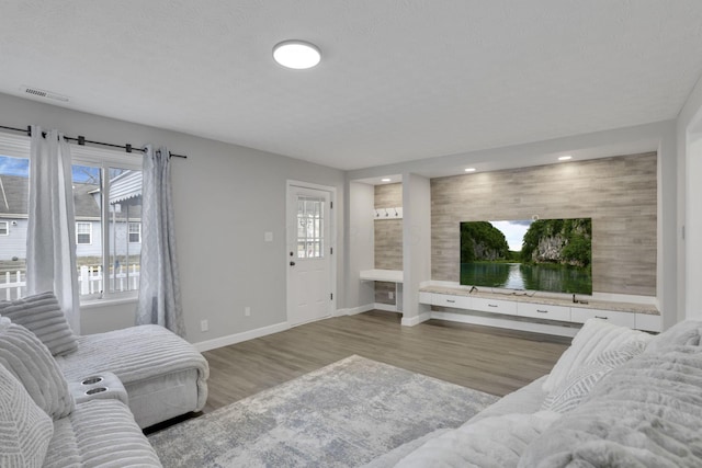 living area featuring visible vents, recessed lighting, baseboards, and wood finished floors