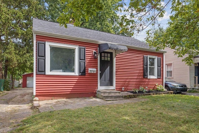 view of front of property featuring entry steps, a shingled roof, and a front lawn