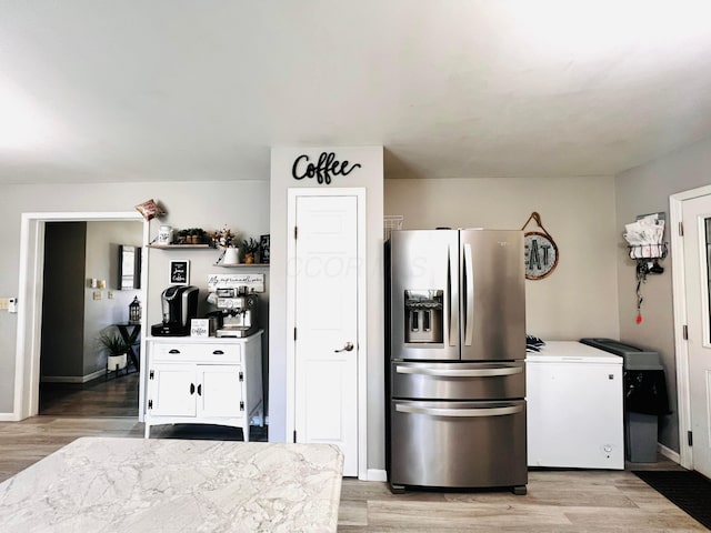 kitchen featuring baseboards, refrigerator, white cabinets, light wood-style floors, and stainless steel refrigerator with ice dispenser