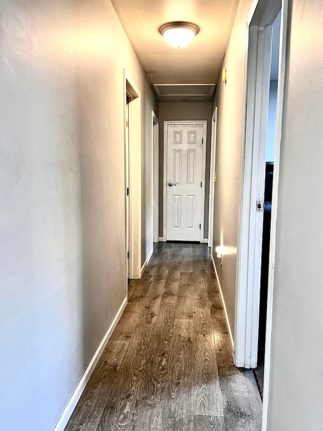 hall featuring attic access, dark wood-type flooring, and baseboards