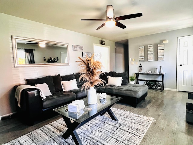 living area with a ceiling fan, baseboards, and wood finished floors