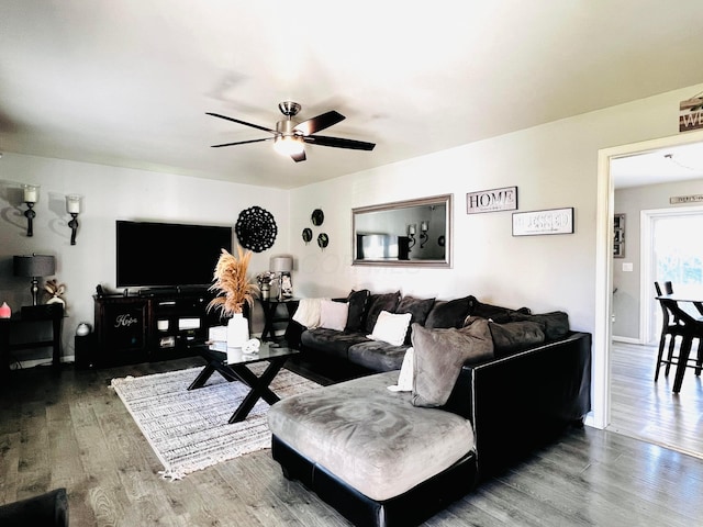 living area with baseboards, a ceiling fan, and wood finished floors