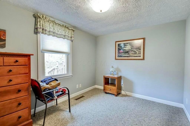 living area with visible vents, baseboards, carpet, and a textured ceiling