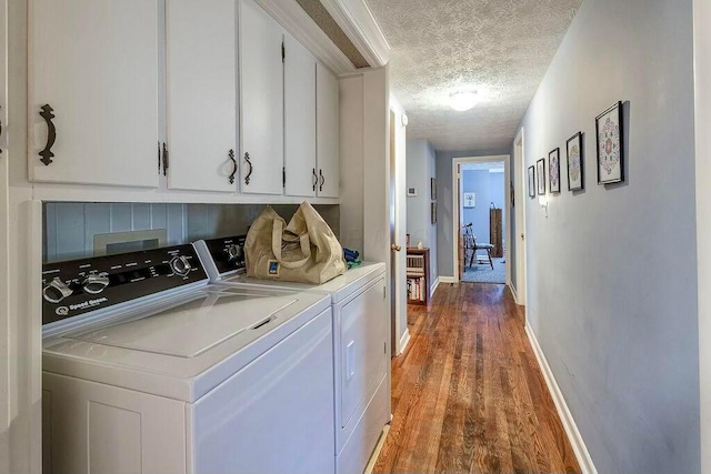 laundry area with wood finished floors, baseboards, cabinet space, a textured ceiling, and independent washer and dryer