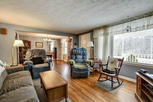 living area featuring visible vents, baseboards, wood finished floors, a notable chandelier, and a textured ceiling