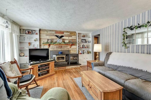 living area featuring a textured ceiling, wallpapered walls, a wood stove, and light wood-style floors