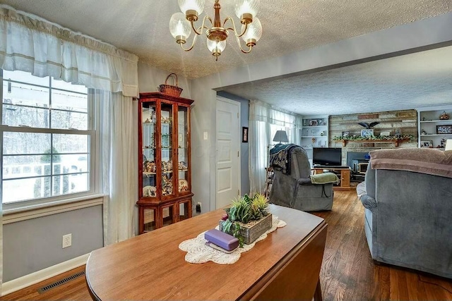 dining room featuring built in features, visible vents, a fireplace, dark wood-type flooring, and a textured ceiling