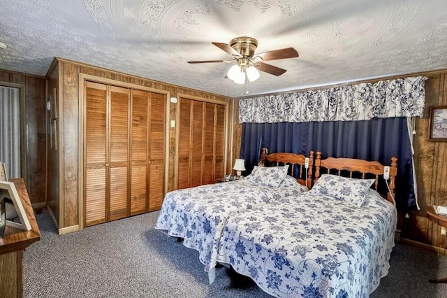 carpeted bedroom featuring two closets, a textured ceiling, crown molding, and a ceiling fan