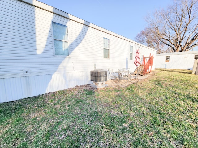 rear view of house with central air condition unit, a lawn, and a patio