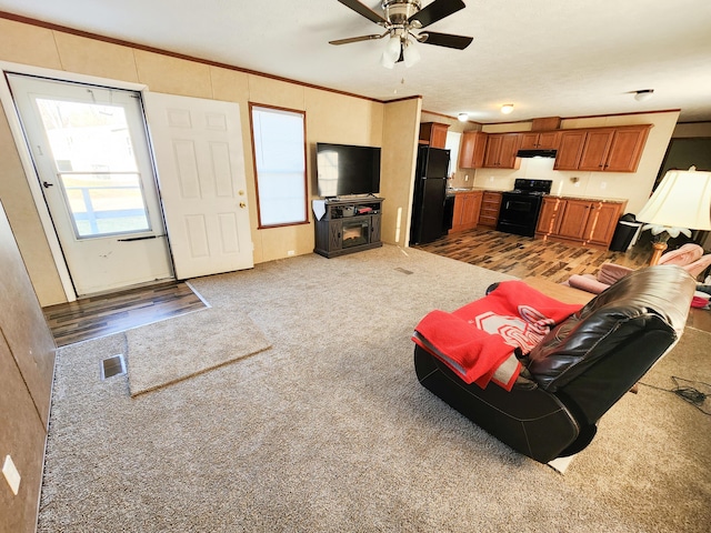 carpeted living room featuring visible vents, a ceiling fan, and ornamental molding