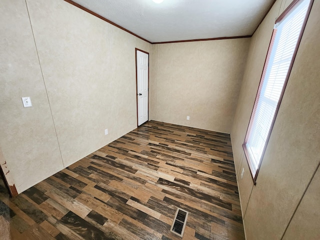 unfurnished bedroom featuring dark wood-style floors, visible vents, and ornamental molding