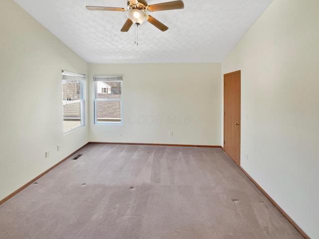 unfurnished room featuring visible vents, light colored carpet, a textured ceiling, and vaulted ceiling