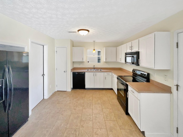 kitchen with black appliances, light countertops, hanging light fixtures, white cabinetry, and a sink