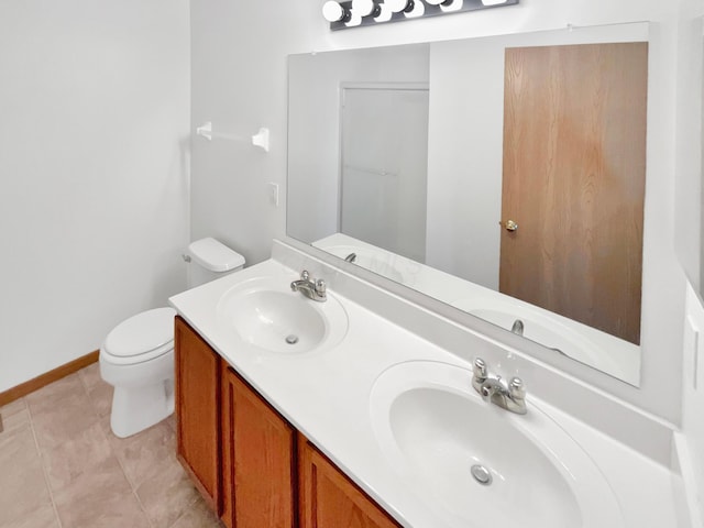 bathroom with a sink, toilet, double vanity, and tile patterned floors