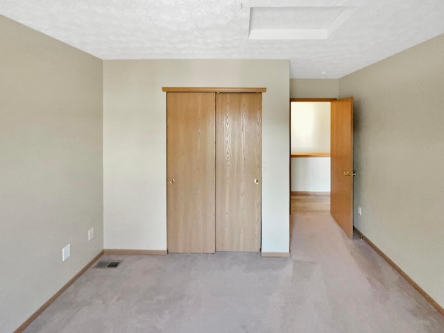 unfurnished bedroom featuring a closet, baseboards, a textured ceiling, and carpet