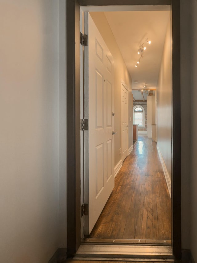 corridor featuring hardwood / wood-style flooring, baseboards, and track lighting