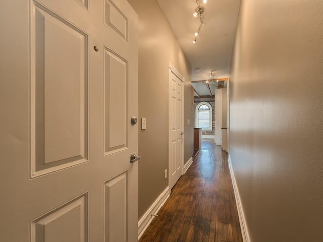 hall featuring dark wood-style floors, track lighting, and baseboards