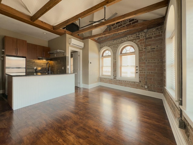 unfurnished living room featuring a wall unit AC, a ceiling fan, dark wood-style floors, brick wall, and a sink