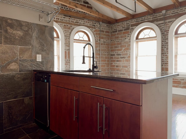 kitchen featuring a sink, dishwashing machine, lofted ceiling with beams, and a wealth of natural light