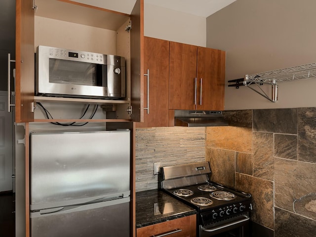 kitchen with under cabinet range hood, brown cabinetry, tasteful backsplash, and appliances with stainless steel finishes