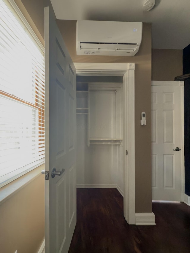 hall featuring an AC wall unit, wood finished floors, and baseboards