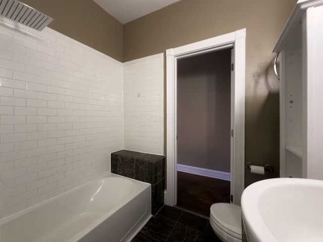 bathroom with baseboards, toilet, marble finish floor, and a bath