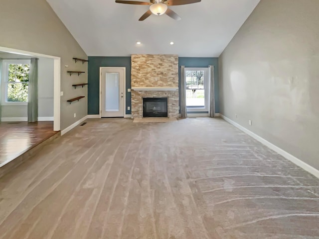 unfurnished living room with ceiling fan, baseboards, a fireplace, wood finished floors, and high vaulted ceiling