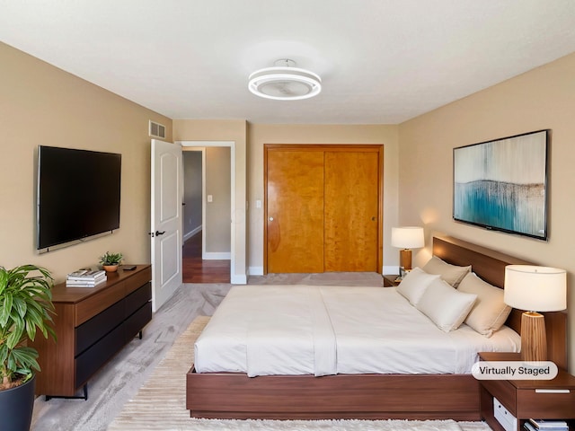 bedroom with visible vents, baseboards, light wood-style floors, and a closet