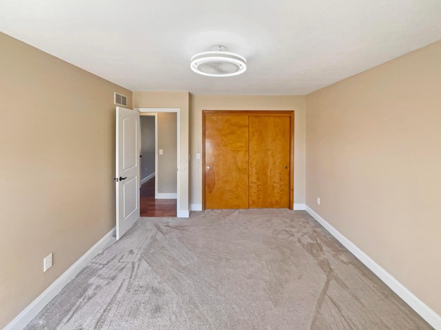 unfurnished bedroom featuring carpet flooring, baseboards, visible vents, and a closet