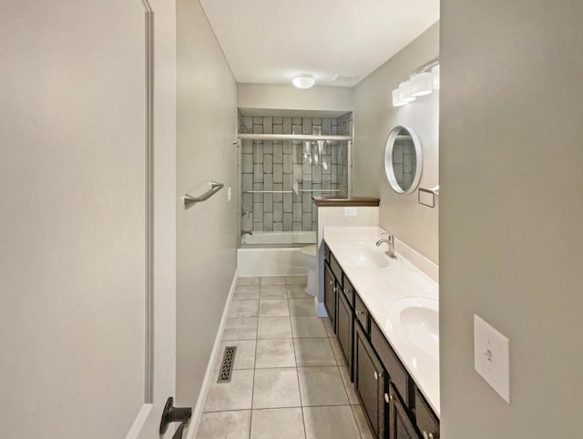 full bathroom featuring baseboards, double vanity, tile patterned floors, combined bath / shower with glass door, and a sink