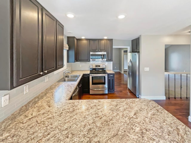 kitchen with dark wood-type flooring, a sink, stainless steel appliances, decorative backsplash, and baseboards