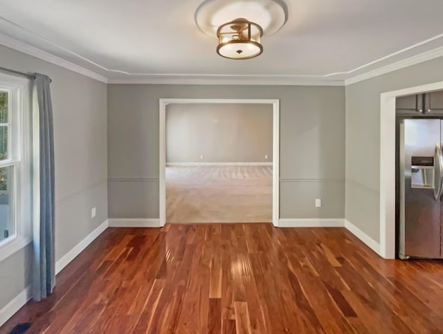 empty room featuring wood finished floors, baseboards, and ornamental molding