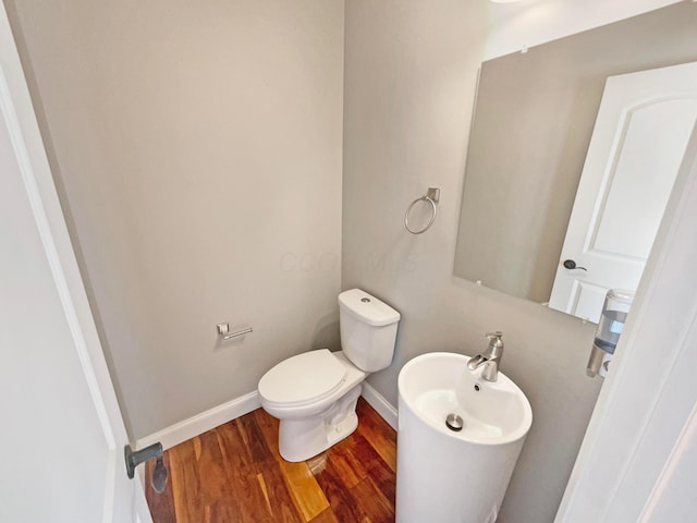 half bathroom featuring baseboards, toilet, and wood finished floors