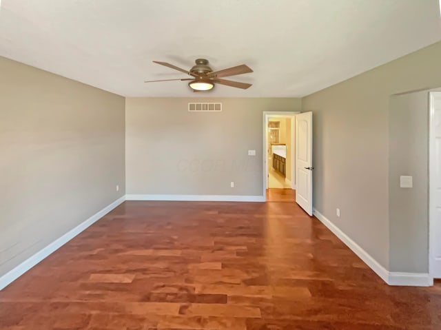 spare room featuring wood finished floors, visible vents, baseboards, and ceiling fan