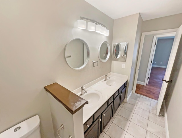 bathroom featuring tile patterned flooring, toilet, baseboards, and a sink