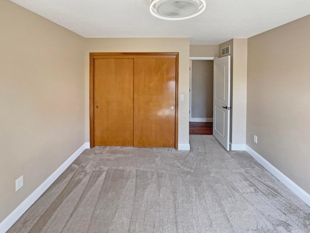 unfurnished bedroom with light carpet, visible vents, a closet, and baseboards