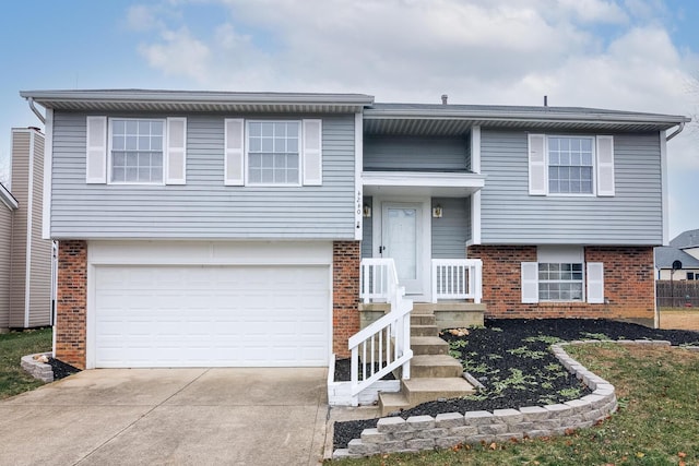 raised ranch featuring brick siding, concrete driveway, and a garage