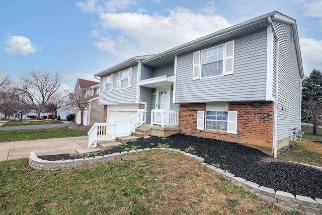 raised ranch featuring brick siding, driveway, and a garage