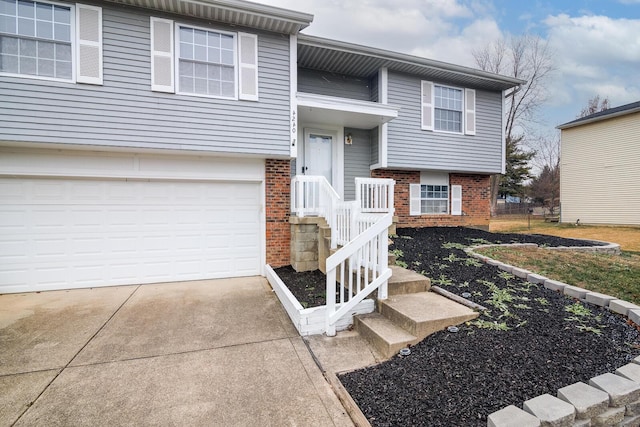 bi-level home with brick siding, an attached garage, and concrete driveway