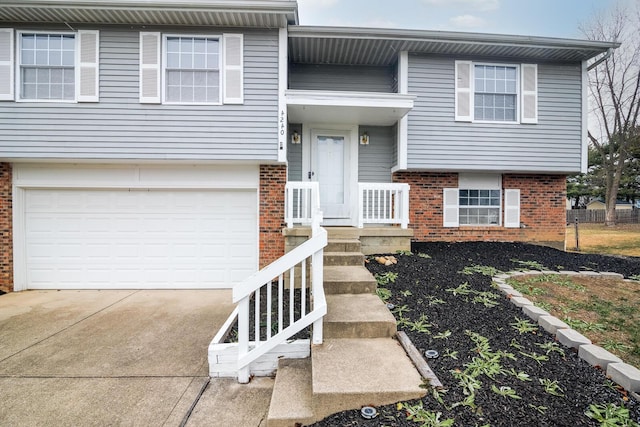 bi-level home featuring an attached garage, brick siding, and driveway