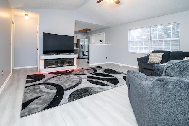 living room with a ceiling fan, lofted ceiling, wood finished floors, and baseboards