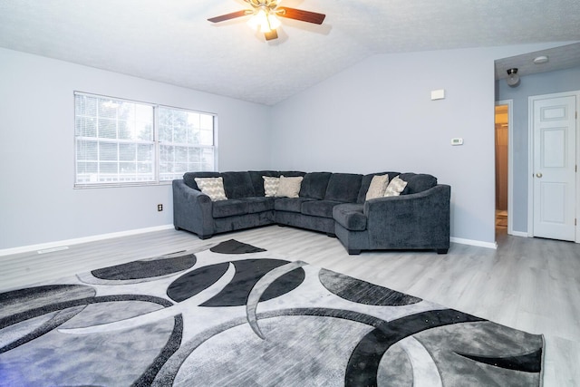 living room featuring a ceiling fan, vaulted ceiling, wood finished floors, and baseboards