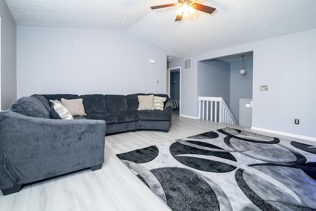 living room with visible vents, baseboards, wood finished floors, and vaulted ceiling