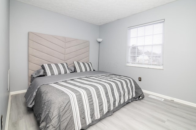 bedroom with visible vents, baseboards, and wood finished floors