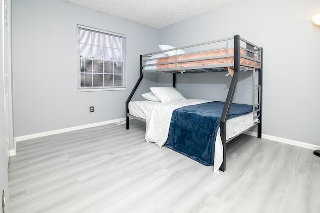 bedroom featuring baseboards, a textured ceiling, and wood finished floors