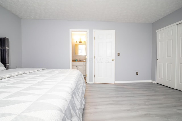 bedroom with a sink, light wood-style flooring, baseboards, and a textured ceiling